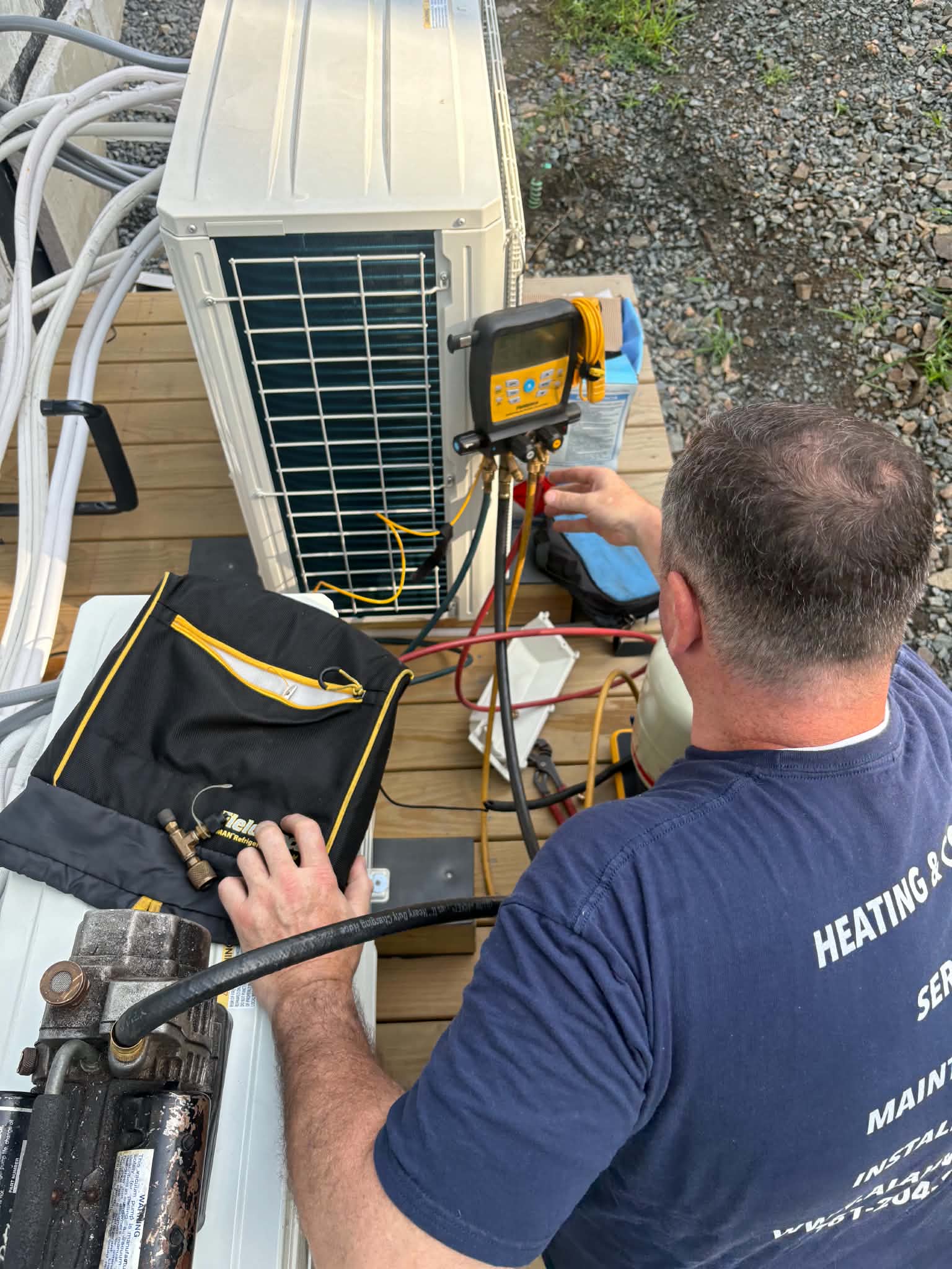 Ala & Sons technician servicing a ductless mini-split outdoor unit with refrigerant gauges